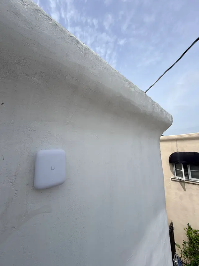 Outdoor wireless access point installed on a rooftop parapet